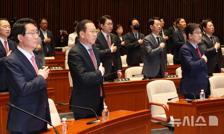 [서울=뉴시스] 조성우 기자 = 권영세(앞줄 왼쪽 두 번째부터) 국민의힘 비상대책위원장과 권성동 원내대표 등 당 소속 의원들이 윤석열 전 대통령이 파면된 4일 서울 여의도 국회에서 열린 의원총회에서 국기에 대한 경례를 하고 있다. 2025.04.04. xconfind@newsis.com