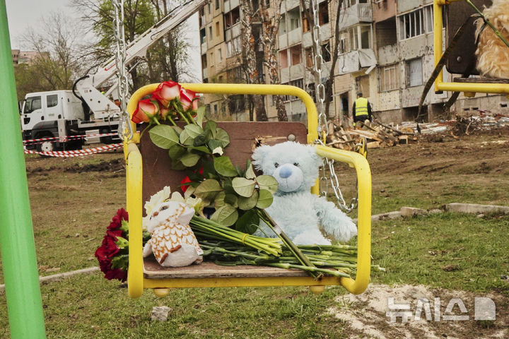 [크리비리흐=AP/뉴시스] 5일(현지 시간) 러시아의 공격으로 피해를 입은 우크라이나 드니프로페트로우스크주 크리비리흐 아파트 앞 놀이터 그네에 희생자들을 기리는 꽃과 장난감이 놓여 있다. 2025.04.06.