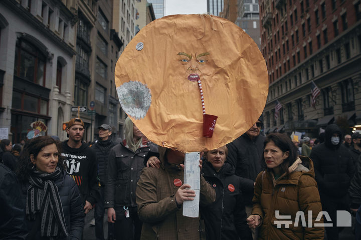 [뉴욕=AP/뉴시스] 5일(현지 시간) 미국 뉴욕에서 도널드 트럼프 대통령과 일론 머스크 정부효율부 수장에 반대하는 '핸즈 오프!'(Hands Off!) 집회가 열려 참가자들이 트럼프 대통령을 풍자한 팻말을 들고 있다. 이날 미국 전역에서 손을 떼라는 의미의 '핸즈 오프' 시위와 행진이 열려 시민권 단체, 노동조합, 성소수자 권익 옹호 단체와 참전용사 단체 등이 참여했다. 2025.04.06.