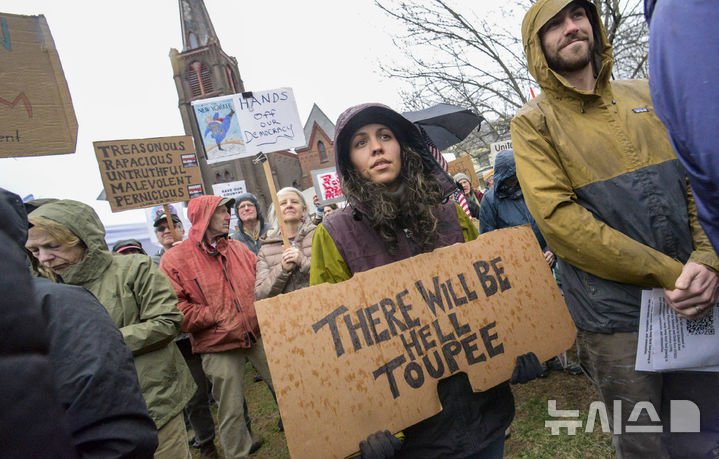 [버몬트주=AP/뉴시스] 5일(현지 시간) 미국 버몬트주 브래틀보로의 한 교회에서 도널드 트럼프 대통령과 일론 머스크 정부효율부 수장에 반대하는 '핸즈 오프!'(Hands Off!) 집회가 열려 참가자들이 팻말을 들고 있다. 이날 미국 전역에서 손을 떼라는 의미의 '핸즈 오프' 시위와 행진이 열려 시민권 단체, 노동조합, 성소수자 권익 옹호 단체와 참전용사 단체 등이 참여했다. 2025.04.06.