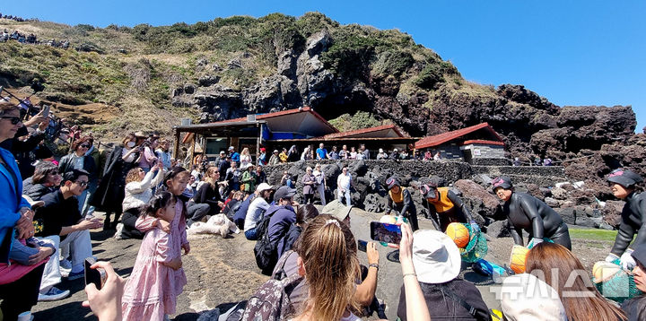 [서귀포=뉴시스] 우장호 기자 = 완연한 봄날씨를 보인 6일 오후 제주 도내 대표적인 관광지 성산일출봉 해변에서 관광객들이 제주 해녀 공연을 관람하고 있다. 2025.04.06. woo1223@newsis.com