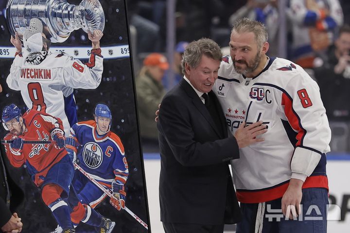 [AP/뉴시스] 6일 뉴욕 엘몬트 경기장에서 벌어진 NHL 하키 경기서 알렉스 오베치킨(오른쪽_)이 새 최다기록인 895호 골을 터트리자 관중석에 있던 894호 공동 최다기록의 웨인 그레츠키가 내려와 축하하고 있다.