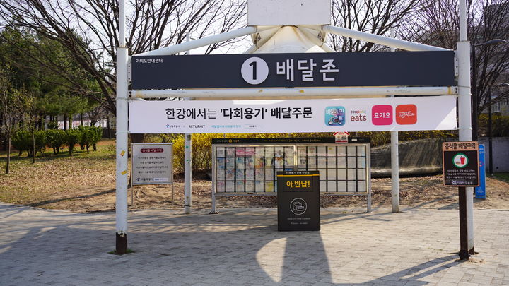 [서울=뉴시스]한강공원 피크닉 존에 설치된 다회용기 반납함 및 관련 현수막. 2025.04.07 (사진 제공=서울시) photo@newsis.com *재판매 및 DB 금지