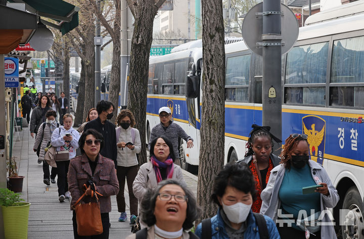 [서울=뉴시스] 김금보 기자 = 외국인 관광객들이 8일 오전 서울 종로구 헌법재판소 맞은편 보행로에서 경찰의 경비 속에 통행하고 있다. 2025.04.08. kgb@newsis.com