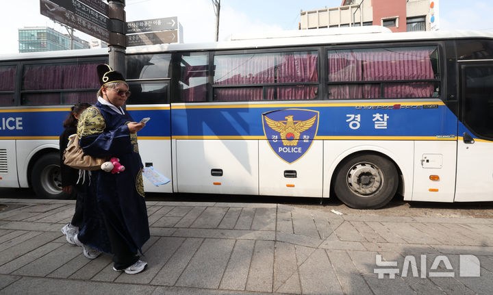 [서울=뉴시스] 김금보 기자 = 외국인 관광객들이 8일 오전 서울 종로구 헌법재판소 맞은편 보행로에서 경찰의 경비 속에 통행하고 있다. 2025.04.08. kgb@newsis.com