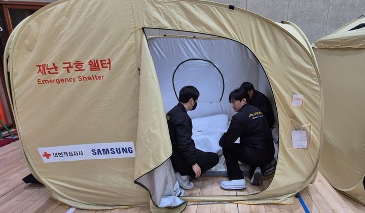 [인천=뉴시스] 경북 지역 산불 피해 주민들을 위해 모금성금에 동참한 ㈜우성이앤씨 직원들이 안동 대피소 현장에 직접 방문하여 재난구호쉘터 내 매트리스 및 온열매트를 설치해주고 있다. (사진=인천적십자 제공) 2025.04.09. photo@newsis.com *재판매 및 DB 금지