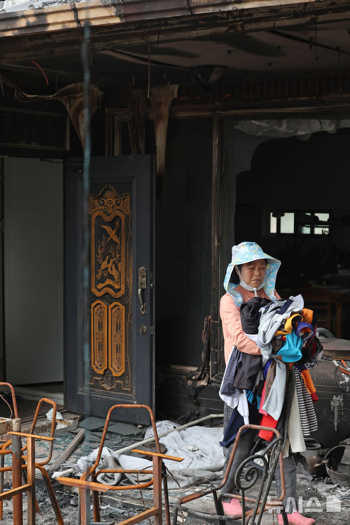 [안동=뉴시스] 김금보 기자 = 산불 피해 주민 박경숙(67)씨가 9일 경북 안동시 만음리의 전소된 집에서 쓸만한 옷가지 등을 챙기고 있다. 2025.04.09. kgb@newsis.com