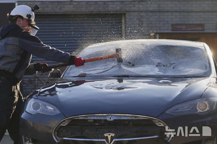 [런던=AP/뉴시스] 10일(현지 시간) 영국 런던에서 한 시위 참가자가 폐차 예정이던 테슬라 자동차를 부수고 있다. 이 시위는 일론 머스크 미 테슬라 최고경영자(CEO)에 반대하는 ‘모두가 일론을 증오해' 단체가 주최했다. 2025.04.11.