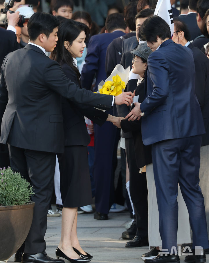 [서울=뉴시스] 최동준 기자 = 윤석열 전 대통령 부인 김건희 여사가 11일 서울 서초구 사저로 들어서며 마중 나온 관계자들에게 꽃다발을 받고 있다. (공동취재) 2025.04.11. photo@newsis.com