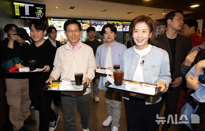 [서울=뉴시스] 황준선 기자 = 제21대 대통령선거 출마를 선언한 김문수 전 고용노동부 장관과 나경원 국민의힘 의원이 12일 오후 서울 동작구 맥도날드 중앙대학교점에서 학생들과 햄버거를 들고 이동하고 있다. 2025.04.12. hwang@newsis.com