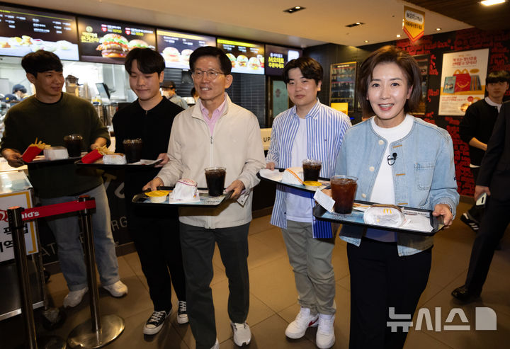 [서울=뉴시스] 황준선 기자 = 제21대 대통령선거 출마를 선언한 김문수 전 고용노동부 장관과 나경원 국민의힘 의원이 12일 오후 서울 동작구 맥도날드 중앙대학교점에서 학생들과 햄버거를 들고 이동하고 있다. 2025.04.12. hwang@newsis.com