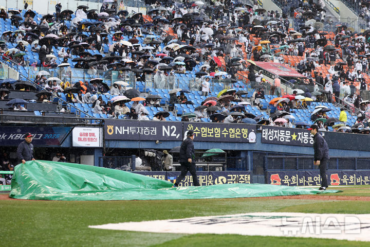 [서울=뉴시스] 김선웅 기자 = 13일 서울 송파구 잠실야구장에서 열린 2025 프로야구 두산 베어스와 LG 트윈스의 경기, 6회초 우천으로 경기가 중단돼 구단 관계자가 방수포를 덮고 있다. 2025.04.13. mangusta@newsis.com