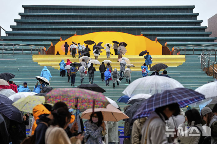 [오사카=AP/뉴시스]13일 개막한 오사카 엑스포는 디지털화를 추진하며 인터넷을 통한 입장권 판매와 사전 예약제를 도입했지만, 행사장 입장을 기다리는 긴 줄이 생겨나 관람까지 오랜 시간이 소요되는 등 '줄 서는 박람회'를 연출했다고 마이니치신문이 14일 보도했다. 비가 내리는 13일 2025 오사카 엑스포 첫날, 우산을 쓴 방문객들이 스페인관에 입장하고 있다. 2025.04.14.