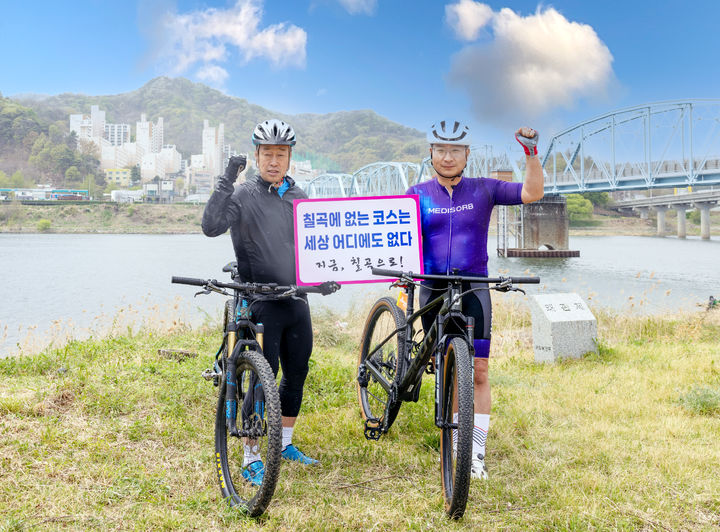 [칠곡=뉴시스] 김태경 회장(왼쪽)과 김원일 대표가 6·25전쟁 당시 북한군의 진격을 막기 위해 폭파했던 '호국의다리' 아래에서 기념사진을 찍고 있다. (사진=칠곡군 제공) 2025.04.14 photo@newsis.com *재판매 및 DB 금지