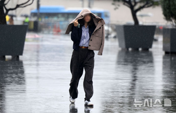 [서울=뉴시스] 김선웅 기자 = 수도권에 봄비가 내린 14일 서울 종로구 광화문광장에서 한 시민이 옷으로 비를 피하고 있다. 2025.04.14. mangusta@newsis.com