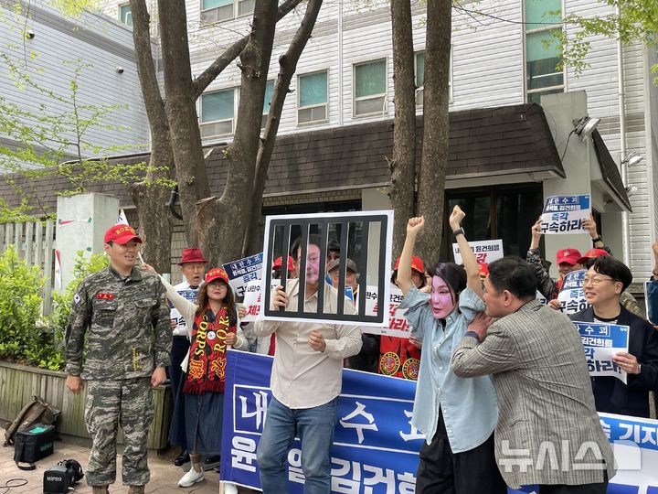 [서울=뉴시스]최은수 기자=촛불행동, 해병대 예비역 연대 등 9개 시민단체가 18일 오전 서울 서초구 서울회생법원 앞에서 윤석열 전 대통령 부부 구속을 촉구하는 기자회견을 열었다. 사진은 윤 전 대통령과 김씨를 형상화한 피켓을 감옥에 넣는 퍼포먼스를 벌이는 모습. 2025.04.18