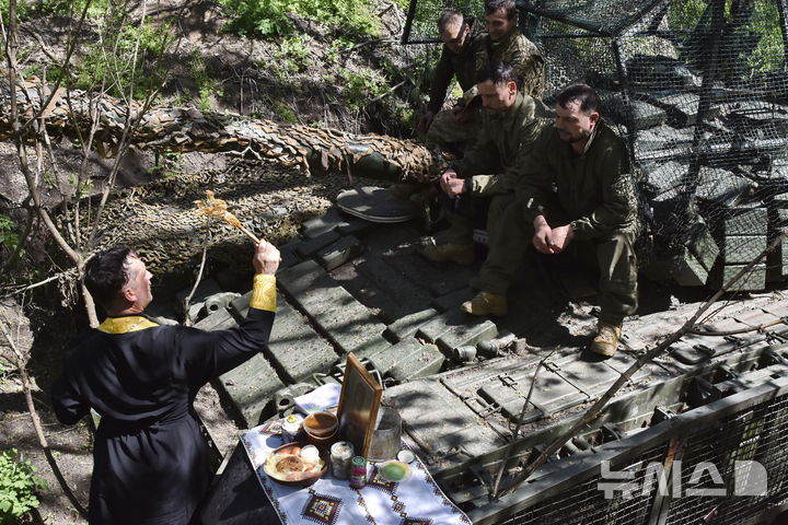 [자포리자=AP/뉴시스] 우크라이나 제65기계화여단 공보실이 제공한 사진에 지난해 4월20일(현지 시간) 자포리자 최전선에서 부활절을 맞아 한 군목이 전차 위에 앉아 있는 병사들을 축복하고 있다. 2026.04.21.