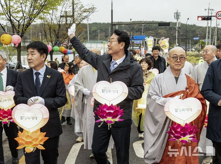 [화성=뉴시스]정명근 화성시장(사진 가운데)과 배정수 화성시의회 의장(사진 왼쪽), 용주사 성효 주지스님 등이 연등음악 축제 연등행렬에서 참석한 시민들에게 인사하고 있다(사진=화성시 제공)2025.04.20.photo@newsis.com
