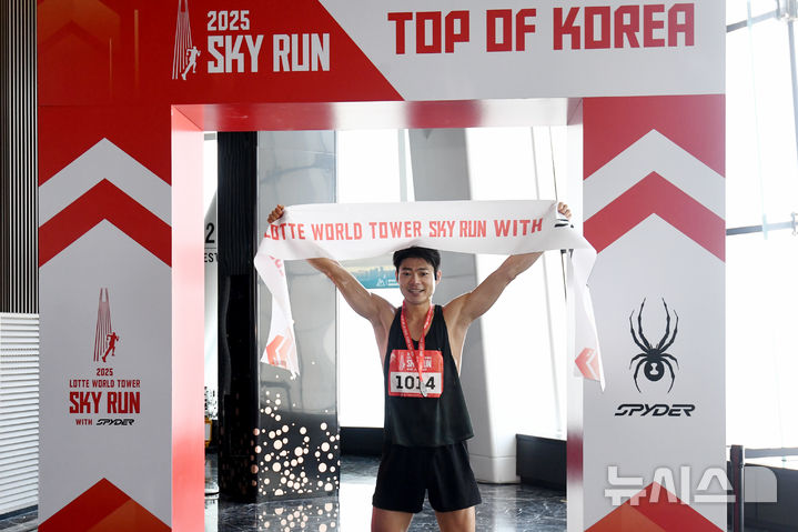 [서울=뉴시스] 황준선 기자 = 20일 오전 서울 송파구 롯데월드타워에서 열린 '2025 롯데월드타워 스카이런 with SPYDER'에서 참가자가 결승선을 통과한 뒤 기념촬영을 하고 있다.(공동취재) 2025.04.20. photo@newsis.com
