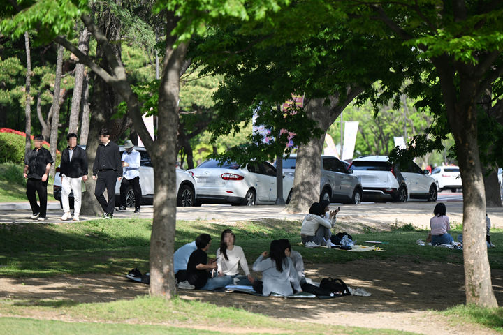[광주=뉴시스] 박기웅 기자 = 광주의 낮 최고기온이 27.6도를 기록하는 등 초여름 날씨를 보인 21일 오후 광주 북구 용봉동 전남대학교 캠퍼스에서 시민들이 잔디밭 그늘에 앉아 더위를 피하고 있다. 2025.04.21. pboxer@newsis.com *재판매 및 DB 금지