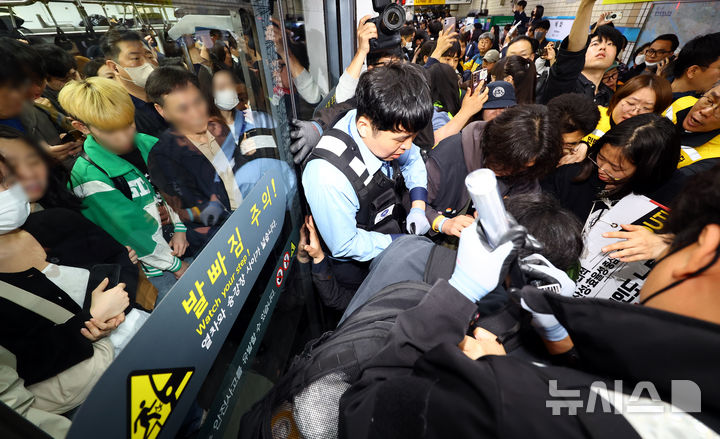 [서울=뉴시스] 박주성 기자 = 전국장애인차별철폐연대(전장연)의 출근길 지하철 탑승 시위가 1년여 만에 재개된 21일 서울 지하철 4호선 혜화역에서 전장연 회원이 지하철 탑승을시도하다 서울교통공사 관계자와 충돌하고 있다. 2025.04.21. park7691@newsis.com