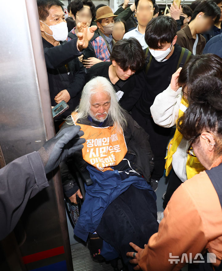 [서울=뉴시스] 박주성 기자 = 전국장애인차별철폐연대(전장연)의 출근길 지하철 탑승 시위가 1년여 만에 재개된 21일 서울 지하철 4호선 혜화역에서 전장연 회원이 지하철 탑승을시도하다 서울교통공사 관계자와 충돌하고 있다. 2025.04.21. park7691@newsis.com