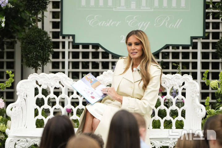 [워싱턴=AP/뉴시스] 도널드 트럼프 미국 대통령의 부인 멜라니아 여사가 21일(현지 시간) 백악관 사우스론에서 열린 연례 '백악관 부활절 달걀 굴리기' 행사에 참여한 어린이들에게 동화를 읽어주고 있다. 2025.04.22.
