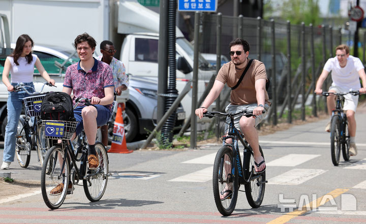 [서울=뉴시스] 이영환 기자 = 서울의 낮기온이 24도까지 오르며 초여름 날씨를 보인 23일 오후 서울 영등포구 여의도한강공원에서 반팔을 입은 외국인들이 자전거를 타고 있다. 2025.04.23. 20hwan@newsis.com