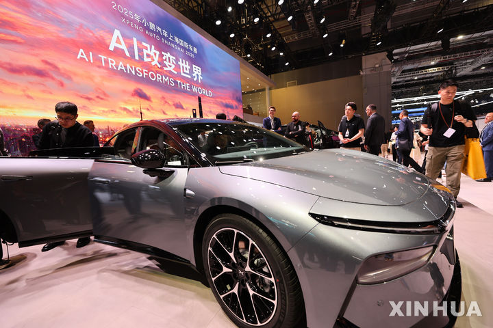 [상하이=신화/뉴시스] 23일 개막한 중국 상하이 모터쇼에서 관람객들이 전시된 차를 문을 열어 살펴보고 있다. 뒷 배경에 인공지능(AI)이 세상을 바꾼다는 문구가 보인다.2024.04.24.
