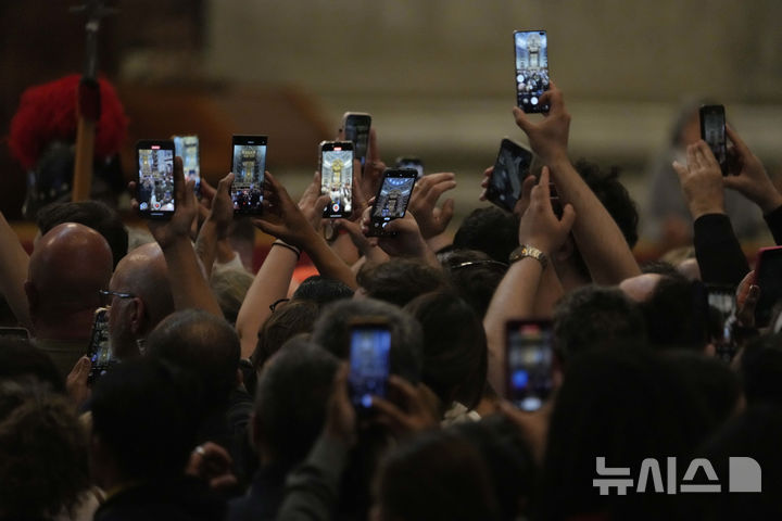 [바티칸시국=AP/뉴시스] 23일(현지 시간) 바티칸 성베드로 대성당에서 신자들이 스마트폰으로 프란치스코 교황의 유해를 담고 있다. 프란치스코 교황의 시신은 사흘간 대성당에 안치돼 일반 신자들의 조문을 받는다. 2025.04.24.</font></font>