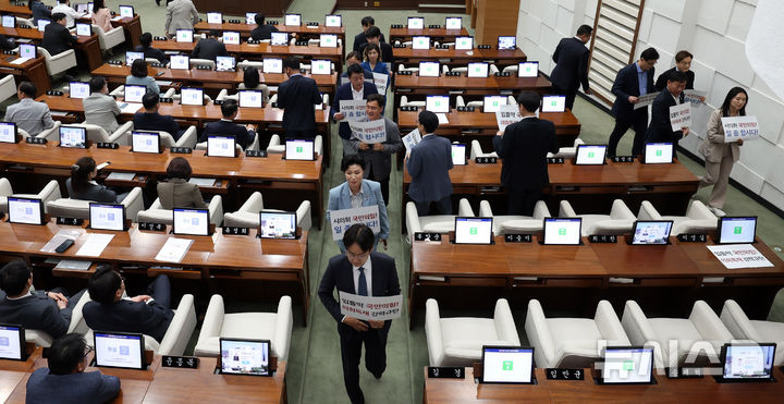 [서울=뉴시스] 추상철 기자 = 25일 오후 서울 중구 서울시의회에서 열린 제330회 시의회 임시회 2차 본회의에서 시의회 야당 의원들이 '입틀막 국민의힘!, 의회독재 강력규탄', '시의회 국민의힘 일 좀 합시다!'라고 적힌 피켓을 들고 퇴장하고 있다. 2025.04.25. scchoo@newsis.com