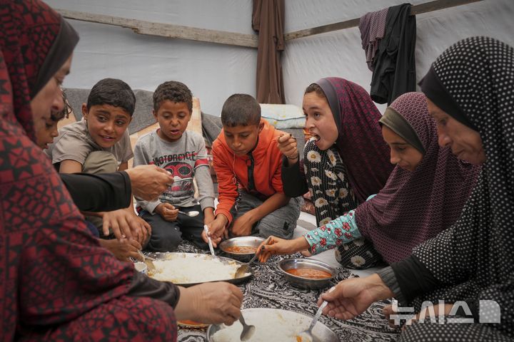 [AP/뉴시스] 가자 칸유니스 인근 무와시 난민촌에서 25일 여성과 아이들이 밥을 먹고 있다
