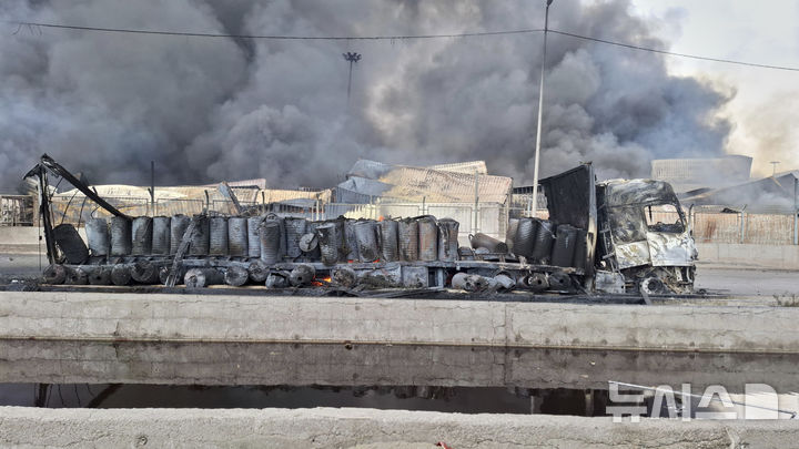 [AP/뉴시스] 26일 이란 남부 항구도시 반다르 아바스 인근 항구에서 큰 폭발 화재가 터진 뒤 27일 불 탄 트럭 뒤편에서 검은 연기가 솟아오르고 있다