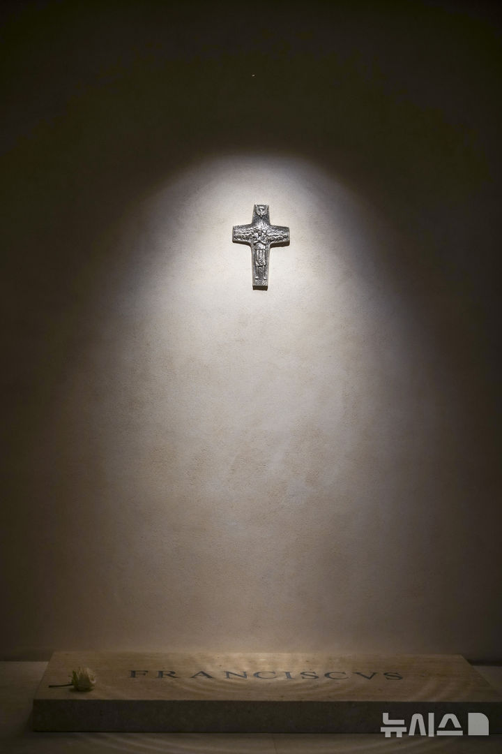 [로마=AP/뉴시스] 27일(현지 시간) 로마 산타 마리아 마조레 대성당(성모 대성전)에서 영면에 든 고(故) 프란치스코 교황의 '프란치스쿠스' 묘비 위에 백장미 한 송이가 놓여 있다. 벽면에 걸린 십자가는 따뜻한 조명 불빛이 비추고 있다. 청빈했던 교황의 뜻에 따라 무덤은 소박하게 꾸며졌다. 2025.04.28.