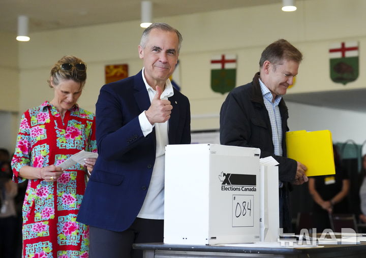 [오타와=AP/뉴시스] 마크 카니 캐나다 총리가 부인 다이애나 폭스(왼쪽)와 함께 28일(현지 시간) 온타리오주 오타와의 한 투표소에서 총선 투표를 하고 있다. 2025.04.29.