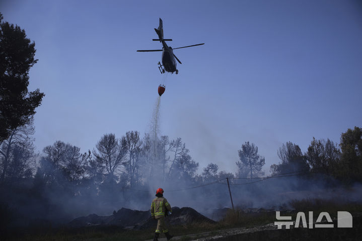 [예루살렘=AP/뉴시스] 이스라엘 예루살렘 인근에서 대형 산불이 확산되는 가운데 베냐민 네타냐후 이스라엘 총리가 국가 비상사태를 선포하고 산불이 도심까지 도달할 수 있다고 경고했다. 1일 예루살렘 외곽지역에서 소방헬기가 진화작업을 진행 중인 모습. 2025.05.01