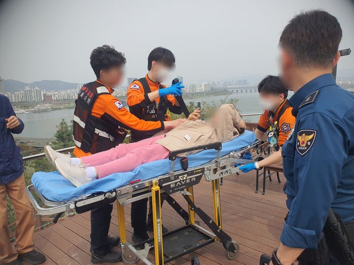 지난달 17일 서울 강남구 삼성해맞이공원에서 의식을 잃고 쓰러진 80대 여성 A씨가 경찰의 응급조치 후 도착한 119 구급대에 의해 병원으로 이송되고 있다.(사진=강남경찰서 제공) *재판매 및 DB 금지