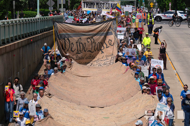 [워싱턴=AP/뉴시스] 1일(현지 시간) 미국 워싱턴에서 열린 노동절 시위 중 시위대가 대형 현수막을 들고 백악관으로 행진하고 있다. 2025.05.02.