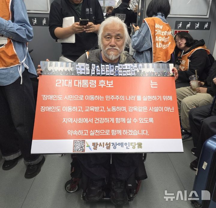 [서울=뉴시스] 고재은 수습 기자 = 박경석 전국장애인차별철폐연대(전장연) 상임공동대표가 2일 오전 서울 지하철 4호선 열차 안에서 21대 대통령 선거 후보에게 장애인권리정책을 요구하는 피켓을 들고 있다. 같은 날 전장연은 서울 종로구 지하철 4호선 혜화역에서 지하철 탑승 선전전을 멈추고 서울 영등포구 국회로 이동했다. 2025.05.02. jeko@newsis.com 