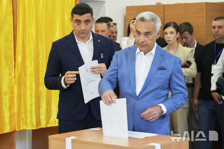 ﻿﻿ [모고소아이아(루마니아)=AP/뉴시스] 제1야당 결속동맹(AUR) 대표 제오르제 시미온(38‧왼쪽) 후보가 4일 지난해 11월 대통령 선거 1차 투표에서 선두였던 컬린 제오르제스쿠(63)와 함께 4일 투표하고 있다.2015.05.05.