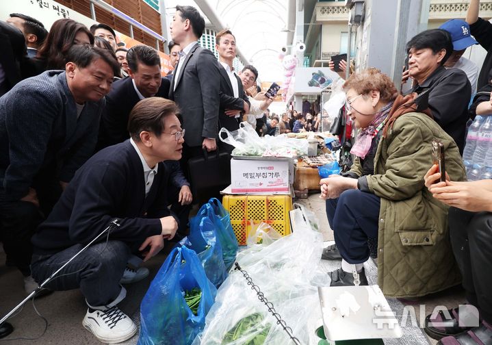 [영월=뉴시스] 조성봉 기자 = 민심을 청취하는 '경청 투어'에 나선 이재명 더불어민주당 대선후보가 4일 강원 영월서부시장에서 상인에게 나물을 구매하며 대화를 하고 있다.2025.05.04. suncho21@newsis.com