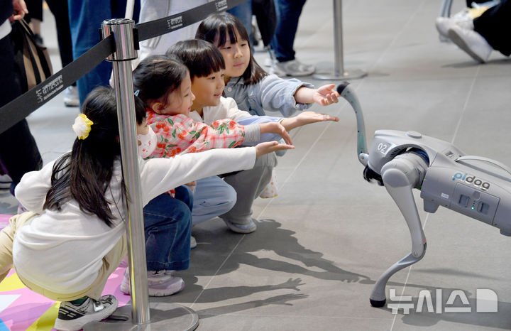 [광주=뉴시스] 변재훈 기자 = 어린이날인 5일 오후 광주 동구 국립아시아문화전당 어린이문화원 일대에서 열린 어린이·가족문화축제 하우 펀(HOW FUN)11 행사장에서 어린이들이 로봇 강아지를 향해 손 내밀고 있다. 2025.05.05. wisdom21@newsis.com