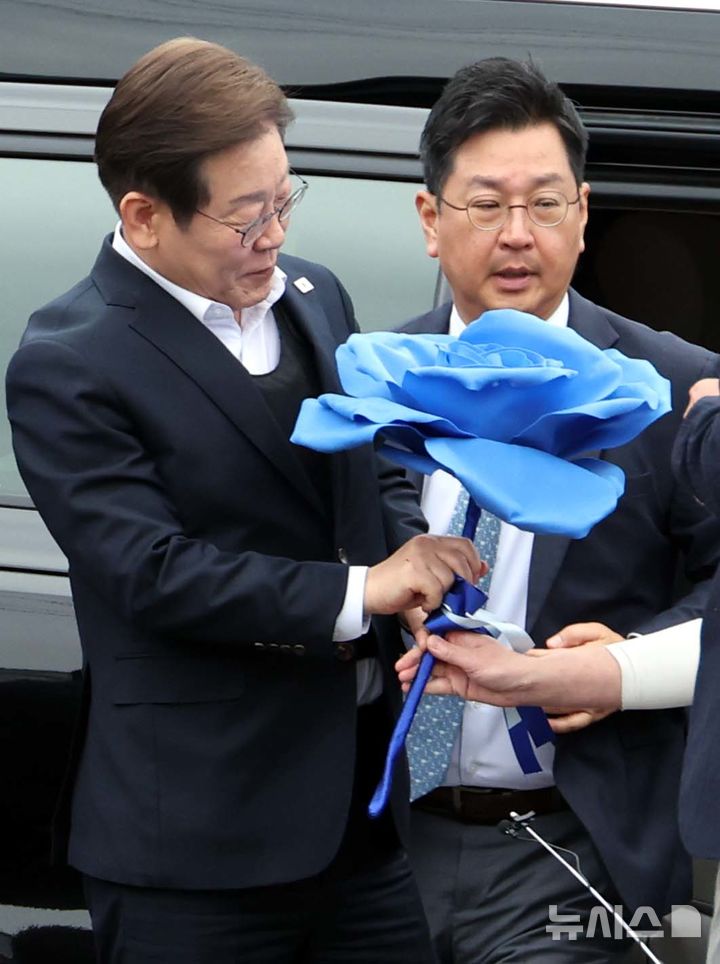 [여주=뉴시스] 조성봉 기자 = 민심을 청취하는 '경청 투어'에 나선 이재명 더불어민주당 대선후보가 5일 경기 여주시 구양리 새마을식당 앞에서 지지자에게 파란색 종이 장미를 선물받고 있다.2025.05.05. suncho21@newsis.com