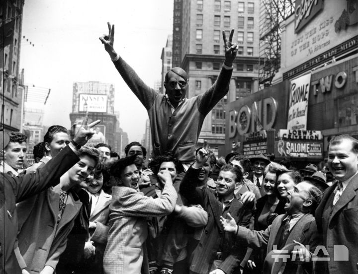 [뉴욕=AP/뉴시스] 사진은 1945년 5월 7일 독일 항복 소식에 환호하는 시민들 사이에서 히틀러 가면을 쓴 청년의 모습. 뉴욕 타임스퀘어. 2025.11.14.