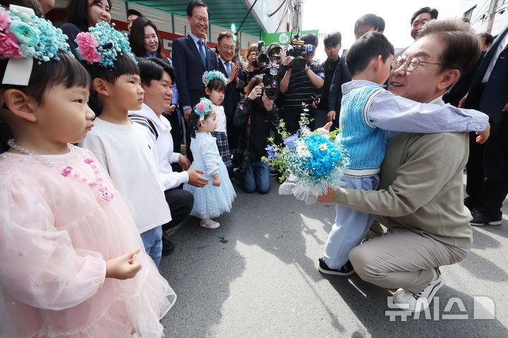 [증평=뉴시스] 조성봉 기자 = 민심을 청취하는 '경청 투어'에 나선 이재명 더불어민주당 대선후보가 6일 충북 증평군 장뜰시장 입구에서 어린이들에게 꽃다발을 선물 받고 있다.2025.05.06. suncho21@newsis.com