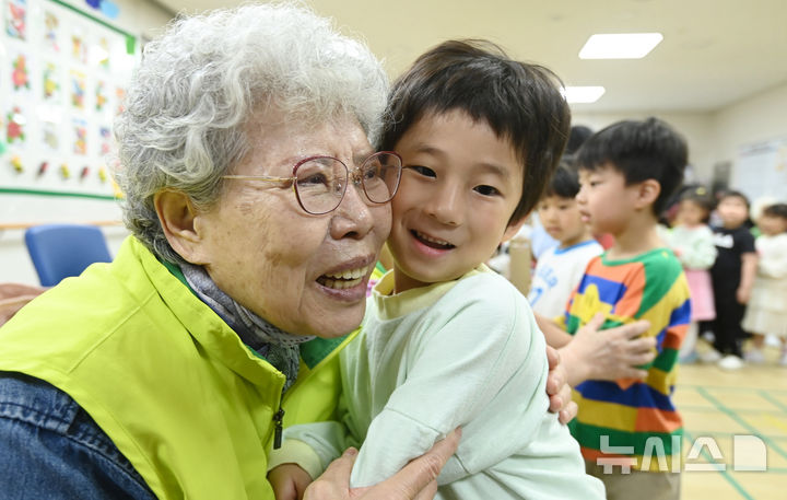 [수원=뉴시스] 김종택 기자 = 어버이날을 하루 앞둔 7일 경기 수원시 팔달노인복지관을 찾은 어린이들이 고사리 손으로 어르신들에게 카네이션을 달아드린 뒤 포옹하고 있다. 2025.05.07. jtk@newsis.com