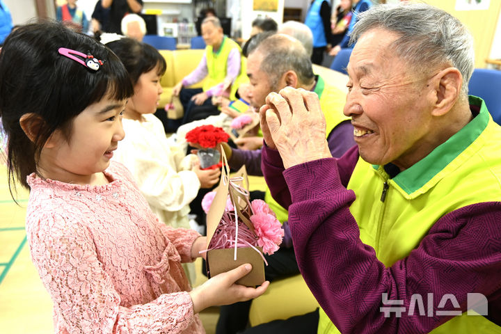 [수원=뉴시스] 김종택 기자 = 어버이날을 하루 앞둔 7일 경기 수원시 팔달노인복지관을 찾은 어린이들이 고사리 손으로 어르신들에게 카네이션을 달아주고 있다. 2025.05.07. jtk@newsis.com
