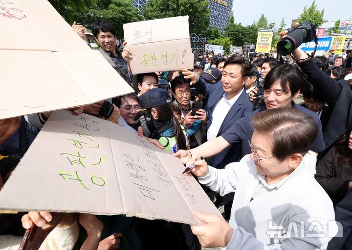 [전주=뉴시스] 조성봉 기자 = 민심을 청취하는 '경청 투어'에 나선 이재명 더불어민주당 대선후보가 7일 전북 전주시 완산구 풍남문 인근에서 공판연기를 환영하는 지지자의 응원 피켓에 사인을 해주고 있다. '공판연기 환영, 대통령은 국민이 뽑습니다'라고 적힌 피켓에 이 후보는 '맞습니다' 라고 쓰고 있다. 2025.05.07. suncho21@newsis.com