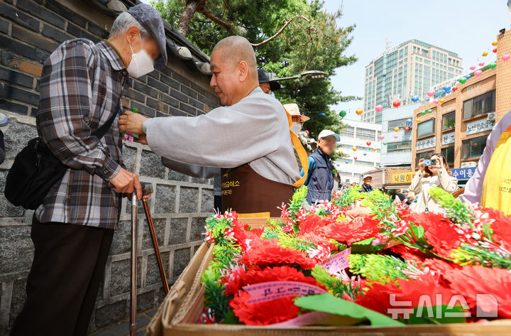 [서울=뉴시스] 황준선 기자 = 어버이날인 8일 서울 종로구 원각사 무료급식소에서 스님이 어르신들에게 카네이션을 달아드리고 있다. 2025.05.08. hwang@newsis.com