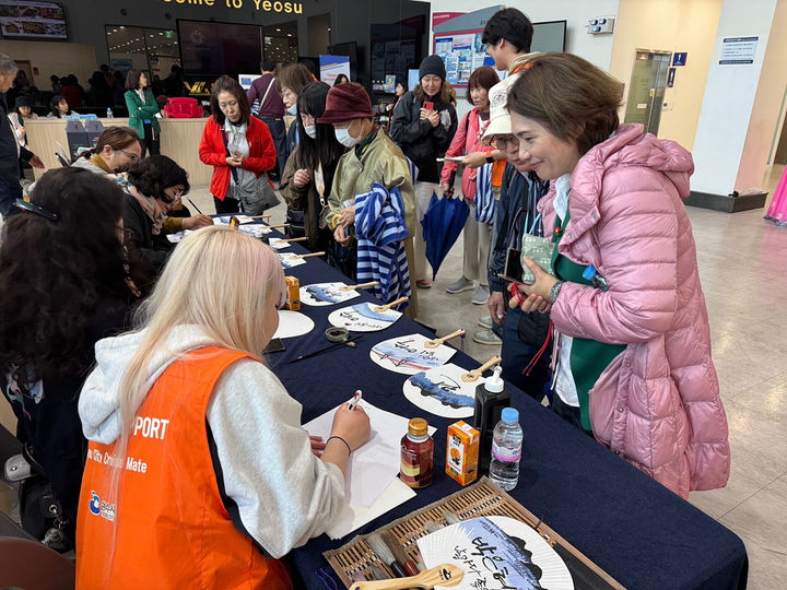 [여수=뉴시스] 9일 엑스포터미널에서 일본 크루즈 '미츠이 오션후지'호 승객들에게 전통 부채에 한글이름을 써주는 행사가 진행되고 있다. (사진=여수시 제공) 2025.05.09. photo@newsis.com *재판매 및 DB 금지